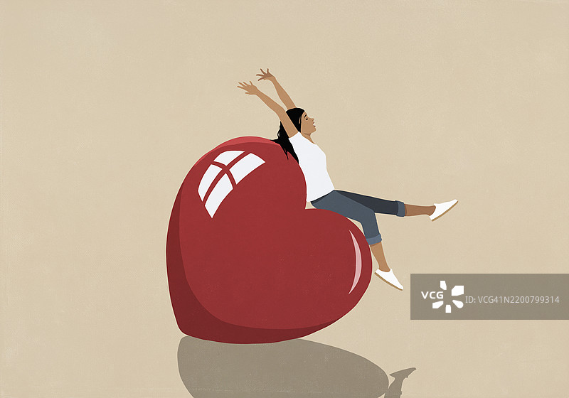 无忧无虑、快乐的年轻女性坐在一个大红心上图片素材