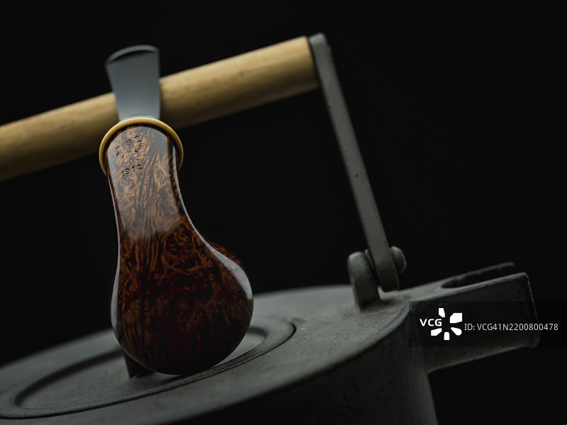 光滑的自由形状橡果烟斗放在复古金属茶壶上图片素材