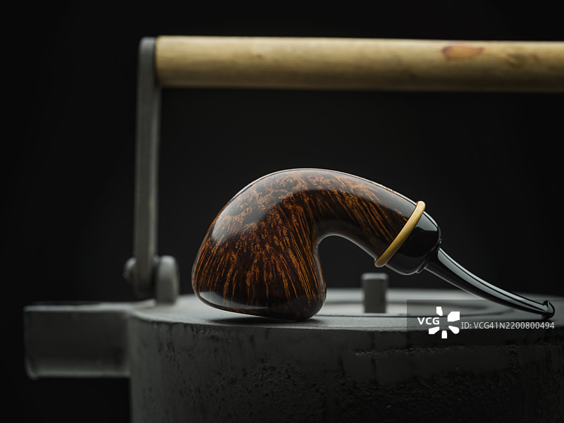 光滑的自由形状橡果烟斗放在复古金属茶壶上图片素材