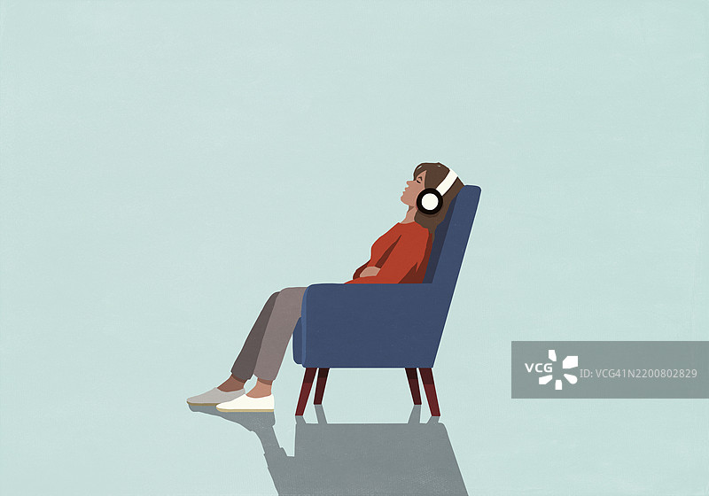 疲惫的女人坐在扶手椅上放松，戴着耳机听音乐图片素材