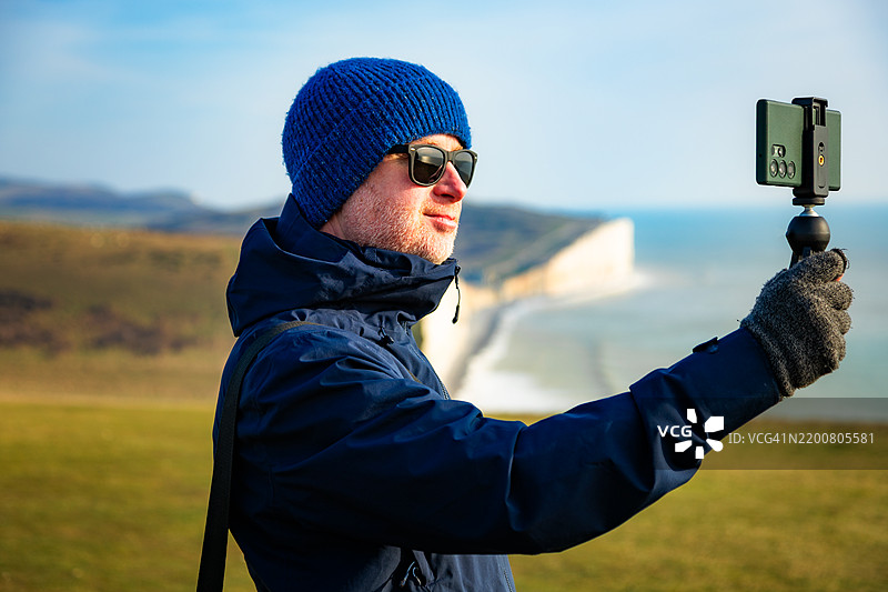 在英国东萨塞克斯的七姐妹悬崖上拍摄视频并创作内容的男子图片素材