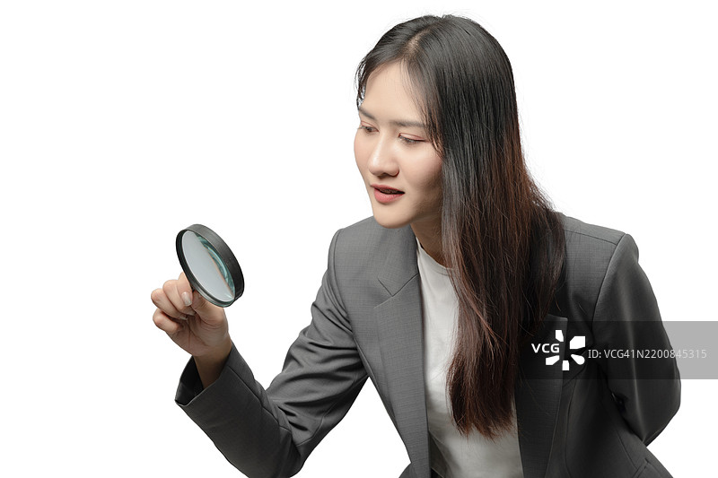 一位穿着灰色西装的女性手持放大镜图片素材