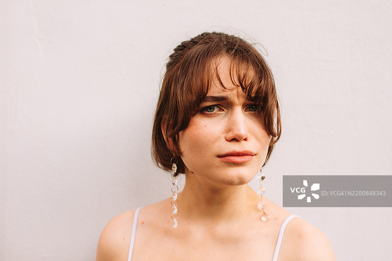 严肃的年轻女性站在灰色墙壁前的肖像图片素材