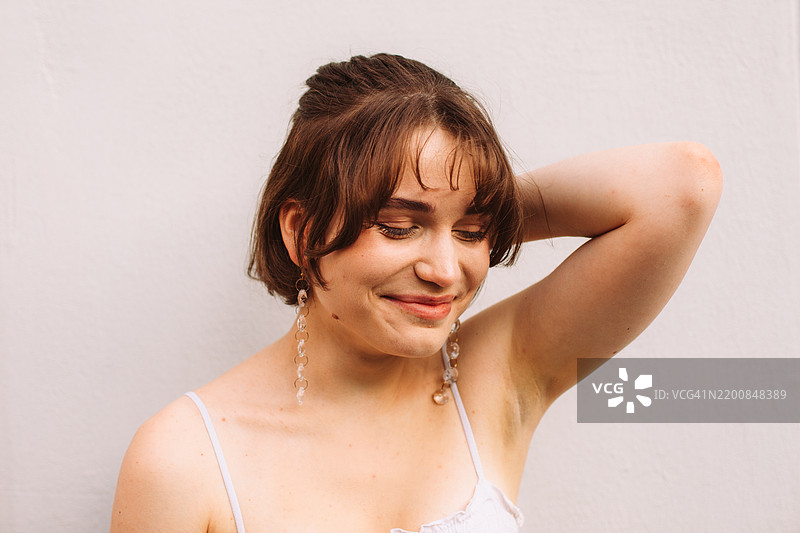 快乐美丽的年轻女性站在灰色墙壁前的肖像图片素材