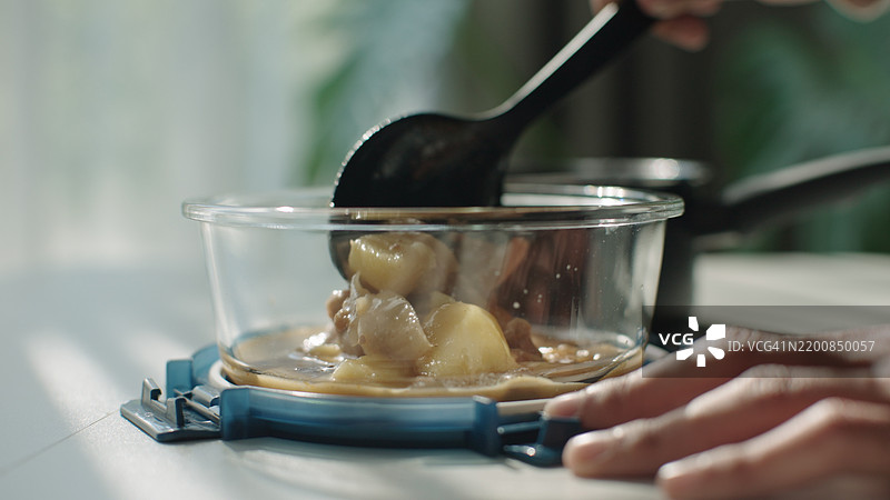 将剩余的汤舀入可持续的玻璃容器中。图片素材