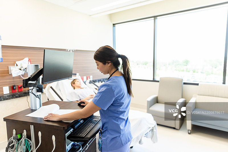 护士在病房使用电脑，病人正在休息图片素材