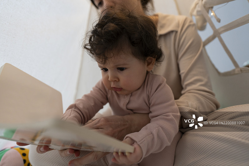 母亲在家里给她的女婴读书的画面图片素材