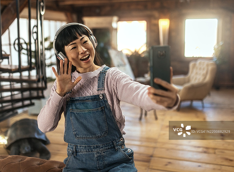 戴着耳机享受音乐的可爱日本女孩自拍照图片素材