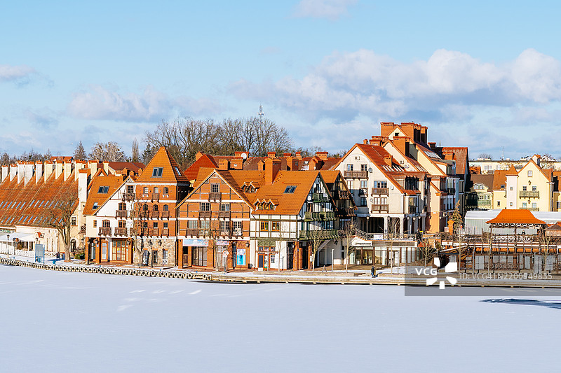 波兰米科瓦伊基沿海岸线的传统红屋顶房屋，前景是结冰的湖泊和明亮的蓝天。图片素材
