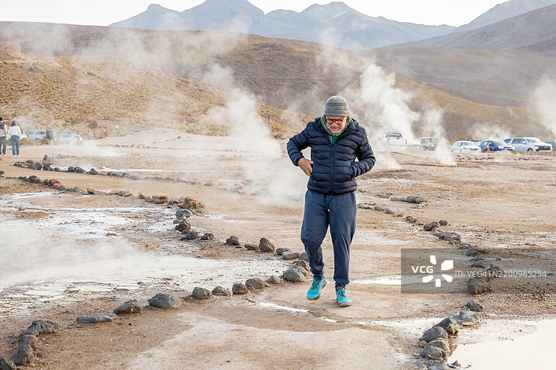 穿着保暖衣物的人走过地热场图片素材