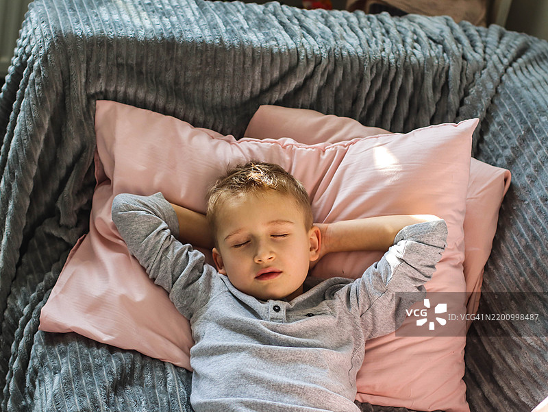 可爱男孩在房间的灰色沙发上睡觉图片素材