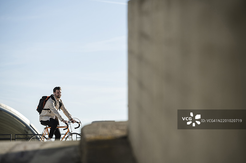 背包男在天空前骑自行车图片素材