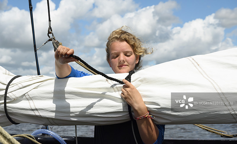 女孩在海上系船上的绳索图片素材
