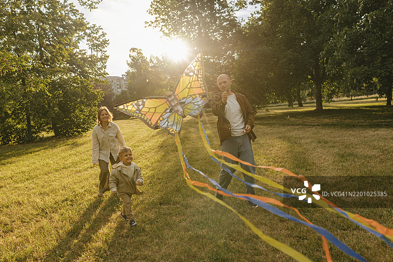 快乐的家庭在公园里放蝴蝶风筝图片素材
