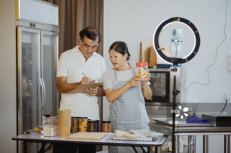 小企业主通过三脚架上的智能手机进行在线销售直播。图片素材