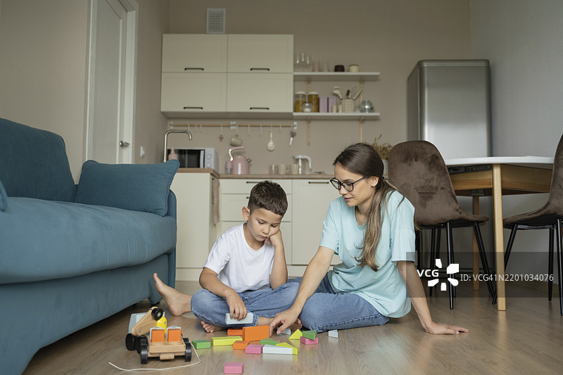 母亲和儿子在家里玩积木玩具图片素材