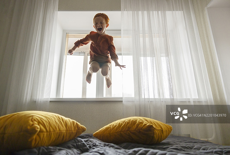 无忧无虑的男孩在家里跳床图片素材