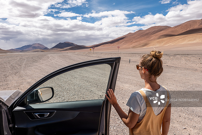 在偏远沙漠景观中站着的女人与汽车图片素材