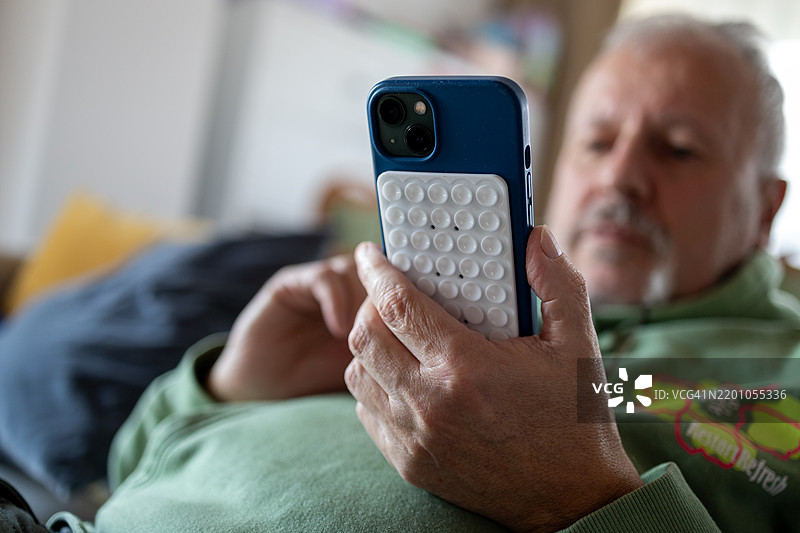 男人手中拿着带硅胶吸盘的智能手机图片素材