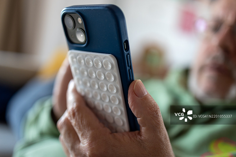 男人手中拿着带硅胶吸盘的智能手机图片素材