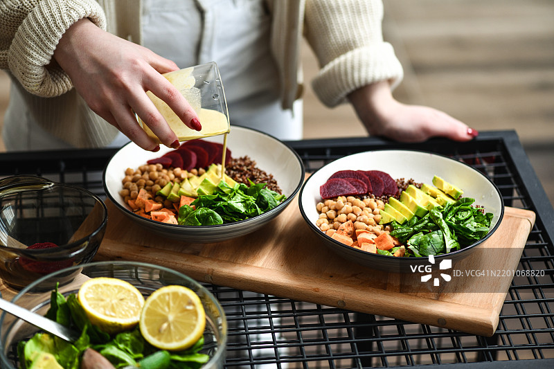 女性在准备美观的沙拉碗，淋上调料以融合口味。图片素材