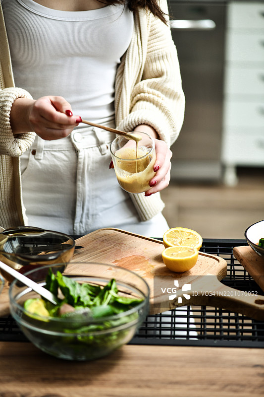 女性尝试用芝麻酱和柠檬汁制作完美口味和一致性的自制沙拉酱图片素材