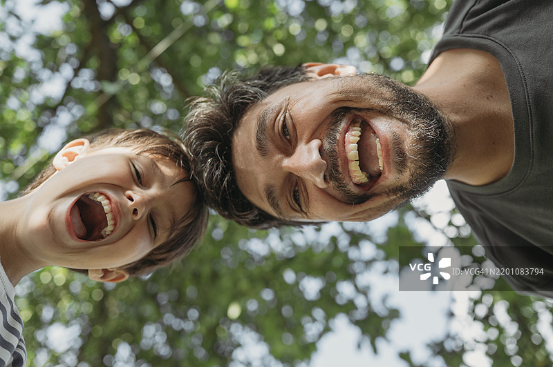 快乐的父亲和儿子在树下享受时光图片素材