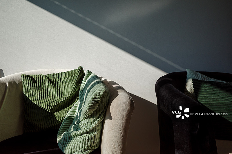 两把现代扶手椅，一把是白色的，另一把是黑色的，配有柔软的绿色条纹靠垫。图片素材