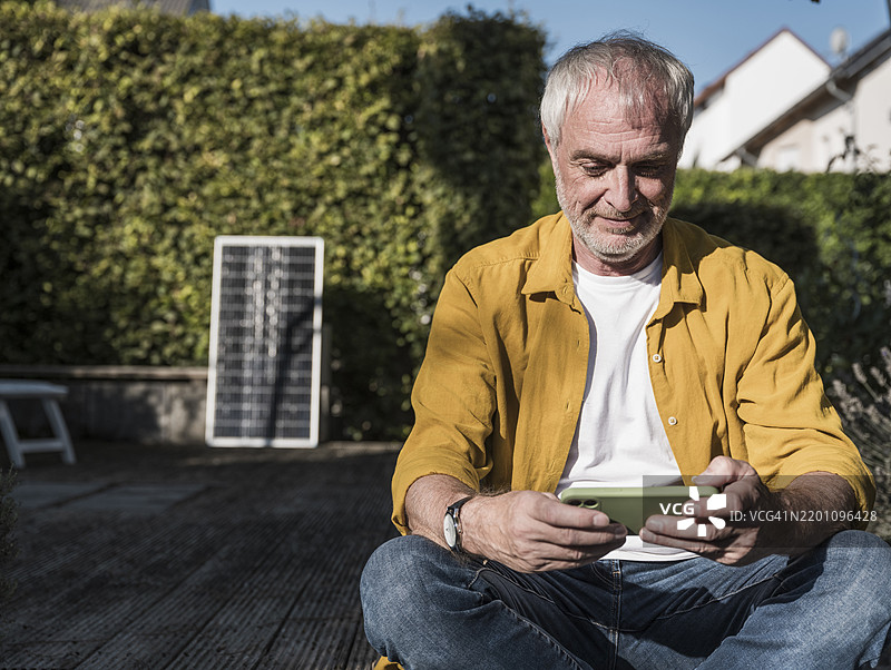 老年男子在后院玩智能手机游戏图片素材