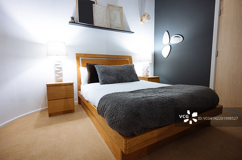 现代卧室室内，配有舒适的床、木质家具、柔和的灯光和简约的装饰，营造出放松的氛围图片素材