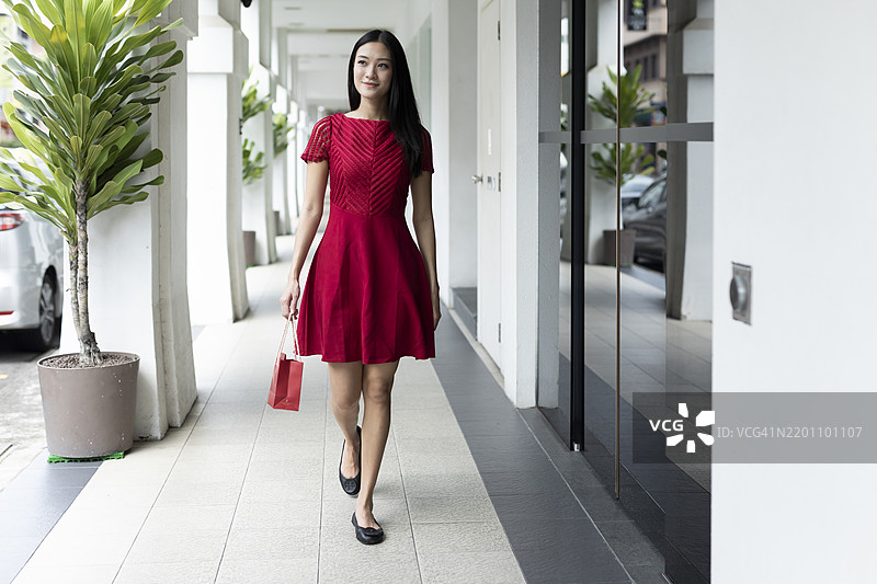 微笑的女性手持礼品袋在走廊中行走图片素材