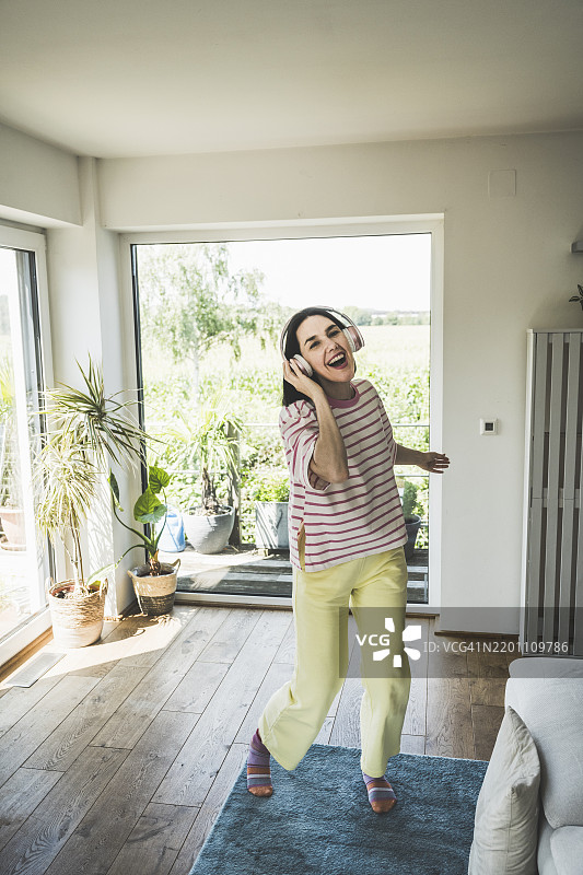 愉快的女性通过无线耳机听音乐图片素材