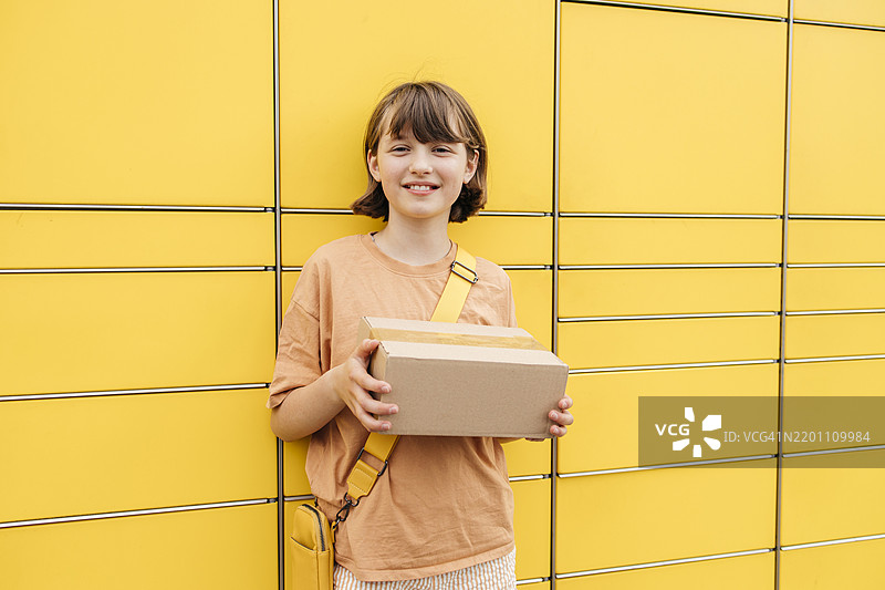 微笑的女孩在终端附近拿着包裹盒图片素材