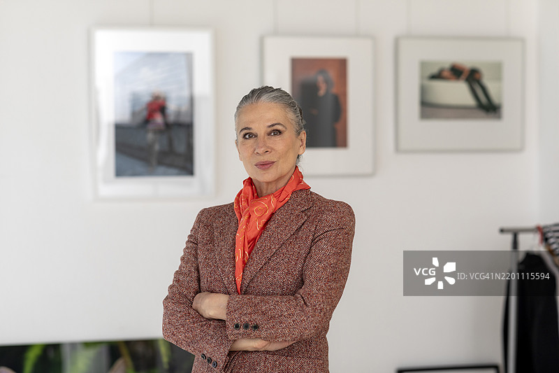 一位双臂交叉的老年女性站在艺术博物馆内图片素材