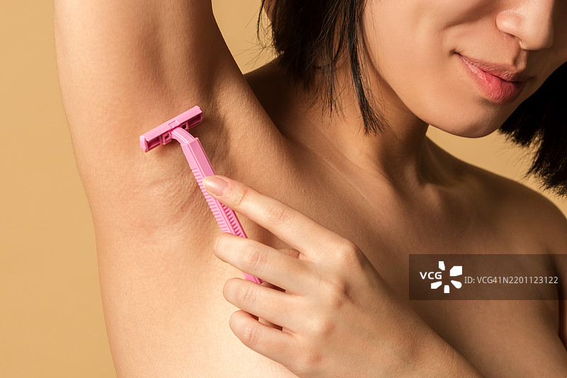 特写肖像：女性用剃刀剃除腋毛图片素材