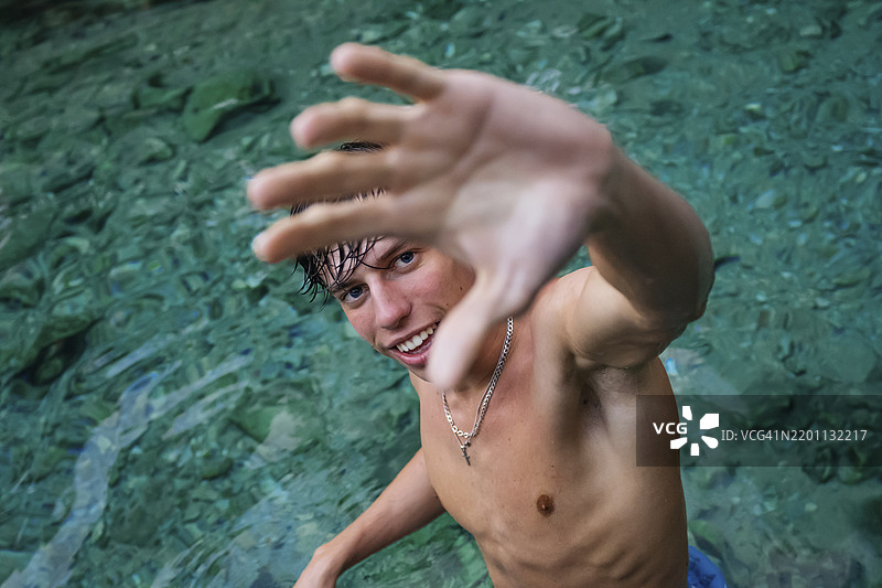 年轻男子在河中伸出手掌做手势图片素材