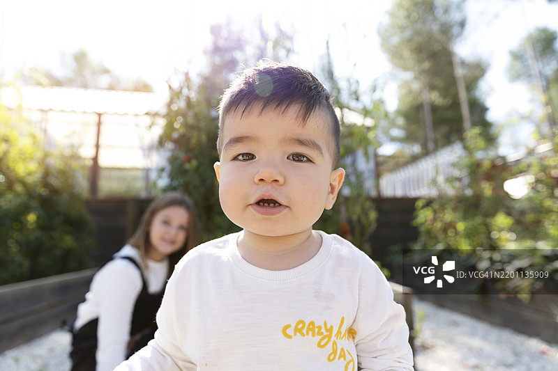 可爱的幼儿男孩穿着白色T恤在后院玩耍图片素材