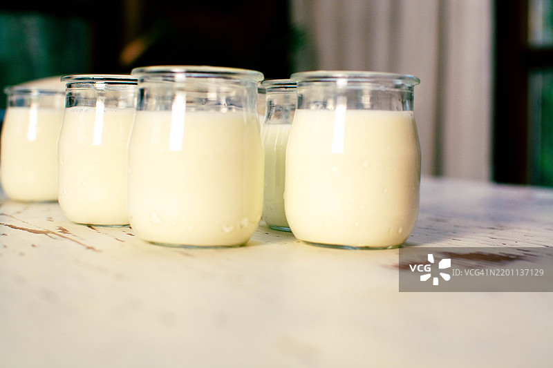 自制酸奶的罐子放在白色木桌上图片素材