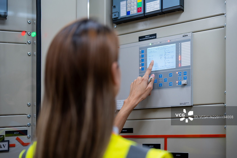 女性电气工程师在设备控制柜检查电气系统，配电变电站中的高压变压器图片素材