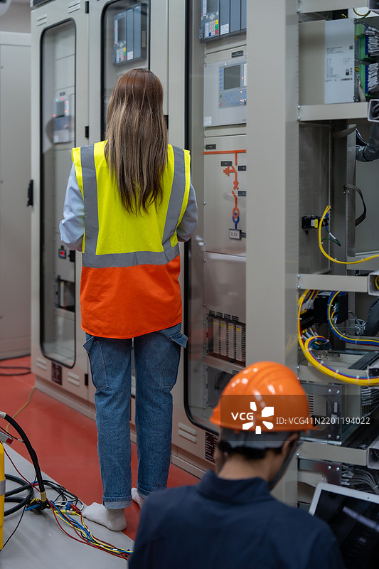 女性电气工程师在设备控制柜检查电气系统，配电变电站中的高压变压器图片素材