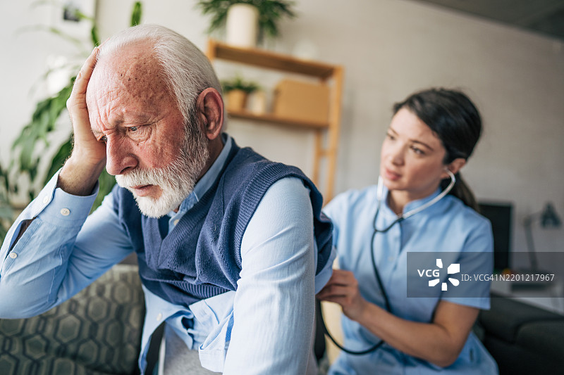 护士在家中用听诊器检查忧虑的老年男性图片素材
