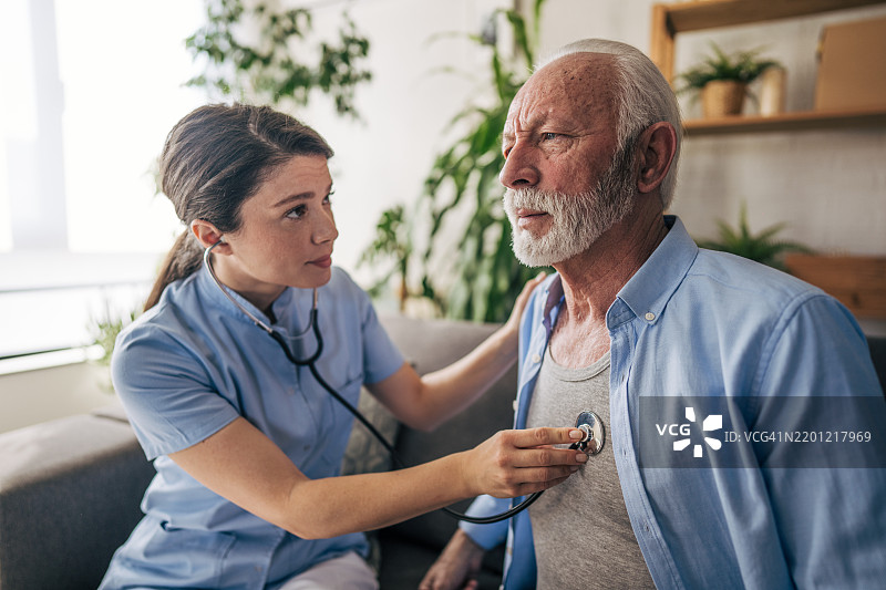 女护士在家中用听诊器为老年男性检查身体图片素材