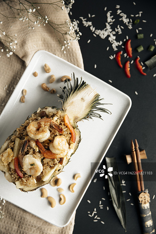 泰式菠萝炒饭（Kao Pad Sapparod），盛放在半个菠萝中，配有虾仁、腰果、蔬菜和米饭，热带风味与异国美食概念，精致的亚洲美食呈现。图片素材