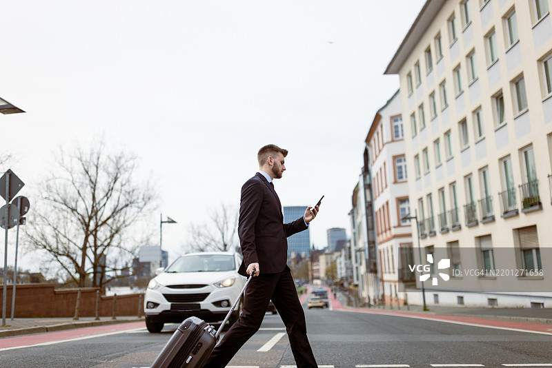 早晨，商人提着行李箱过马路图片素材