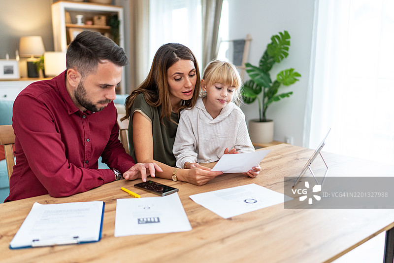 年轻家庭与女儿感到压力，管理预算和支付账单及税款。图片素材