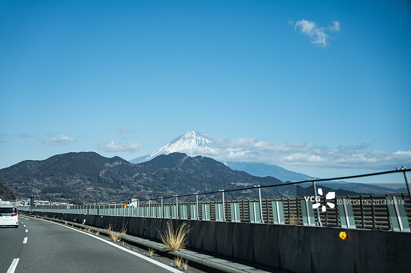 从车内看到的日本神奈川县雪覆盖的富士山和城市道路的景象图片素材