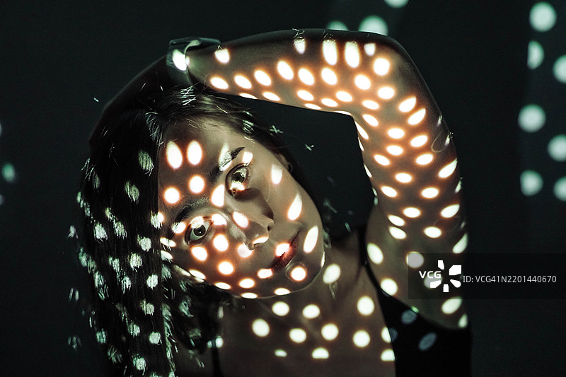 女性面孔在黑暗中光点的投影中。图片素材