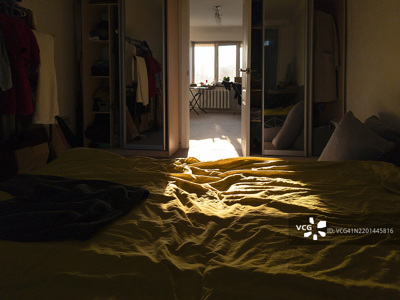 温暖的金色光线洒在温馨卧室里凌乱的床上，邀请着宁静与安详的早晨时光。图片素材