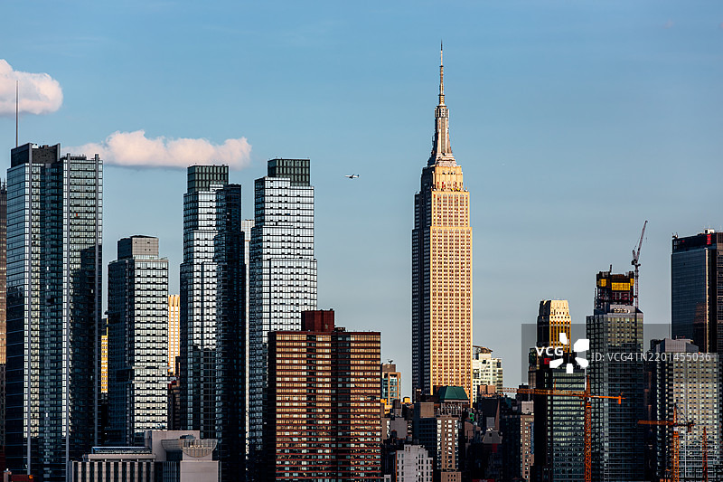 阳光明媚、蓝天清澈的曼哈顿天际线，帝国大厦矗立于纽约市，美国图片素材