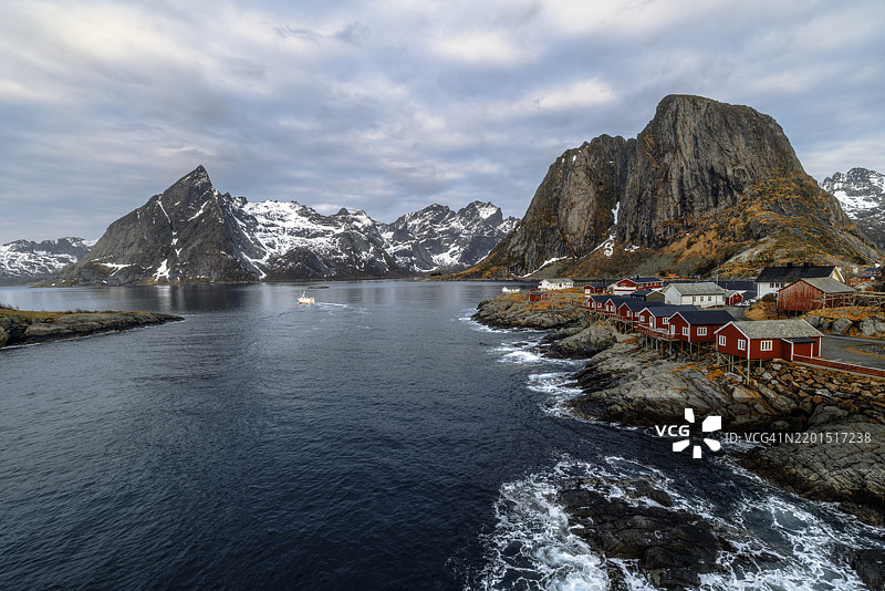 风景如画的海滨渔村，红色小屋与壮丽的山脉背景图片素材